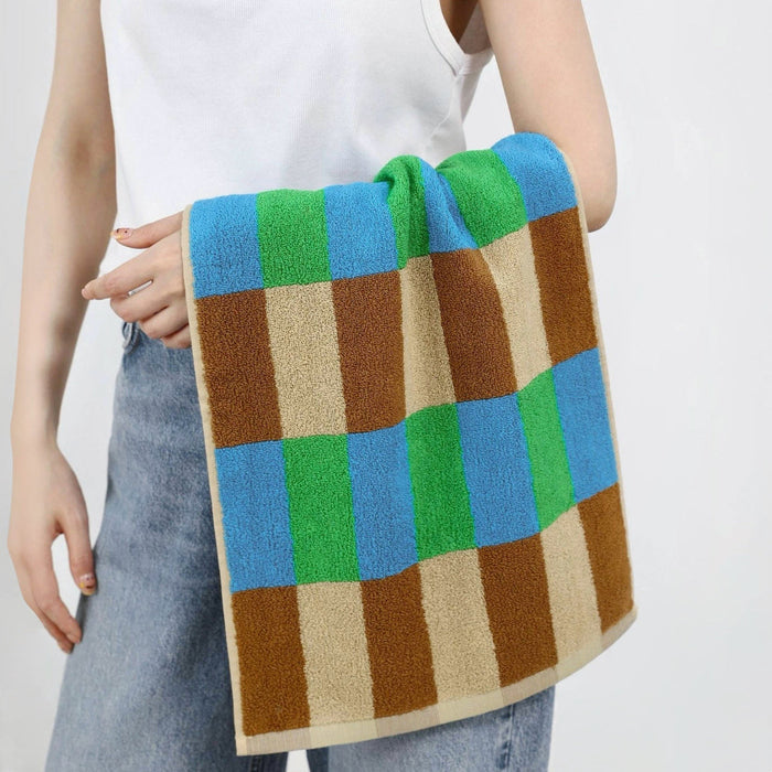 Model holding a Color Game Plaid Face Towel in blue-green, easy for gym, travel, and weekends.