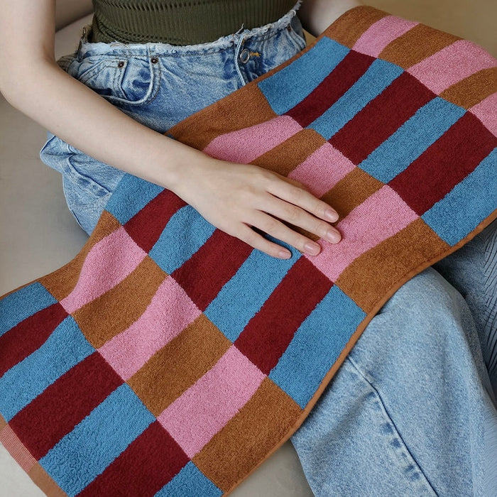 Model holding a Color Game Plaid Face Towel in pink-blue, ideal for beach days and poolside lounging.