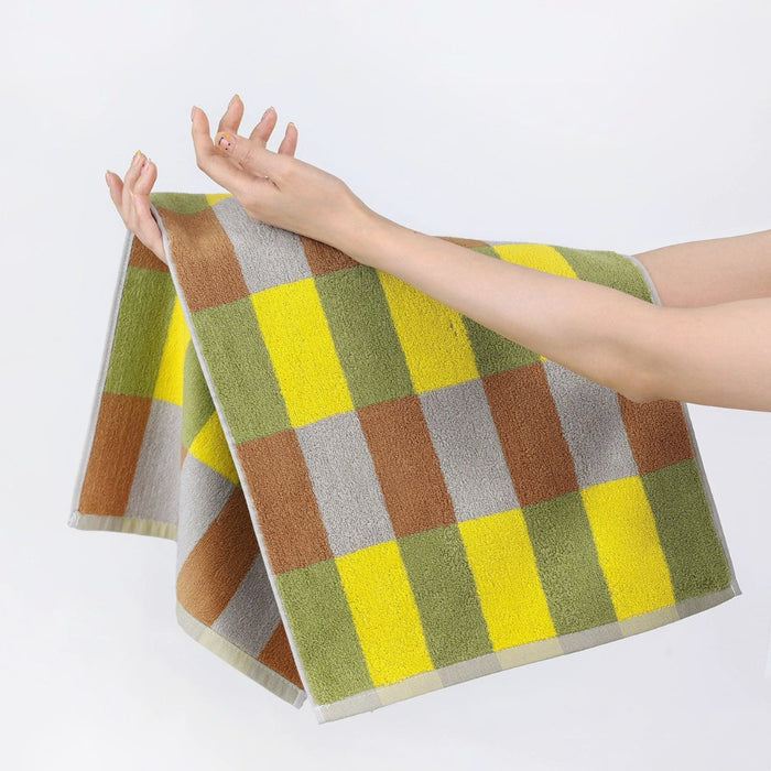 Model holding a Color Game Plaid Face Towel in yellow-green, ideal for beach days and poolside lounging.