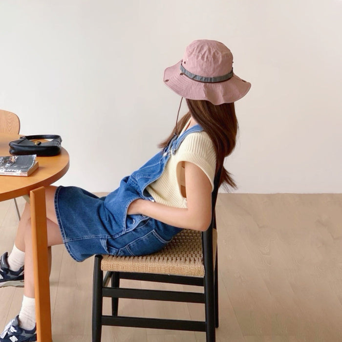 Model sitting at a table wearing the pink-toned bucket hat.