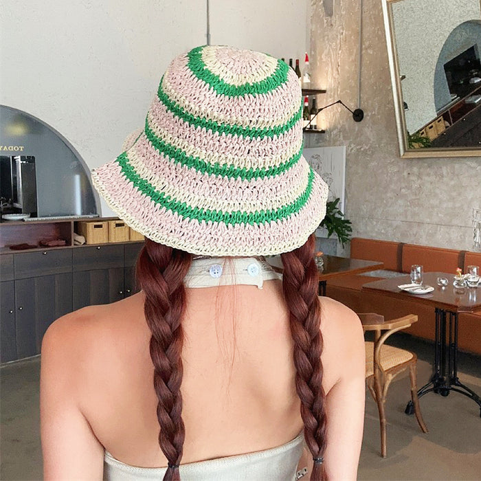 Back view of model wearing black striped straw hat, highlighting the fine weave and flexible foldable design.
