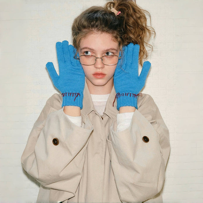 Model wearing colored-thread hemming gloves in blue with contrast stitching; warm knit for winter outfits.