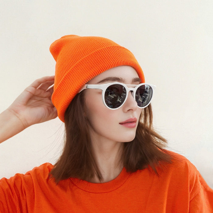 Model wearing orange multi-color beanie. Bright energetic tones designed for high-visibility and warmth.
