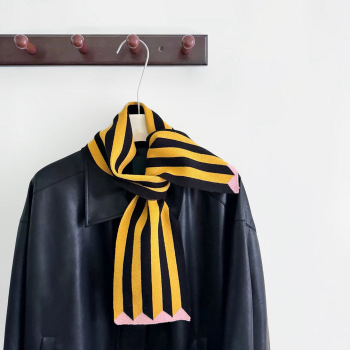 Angled view of ColorPop striped polyester scarf, black and yellow with pink tips, draped over a black jacket.