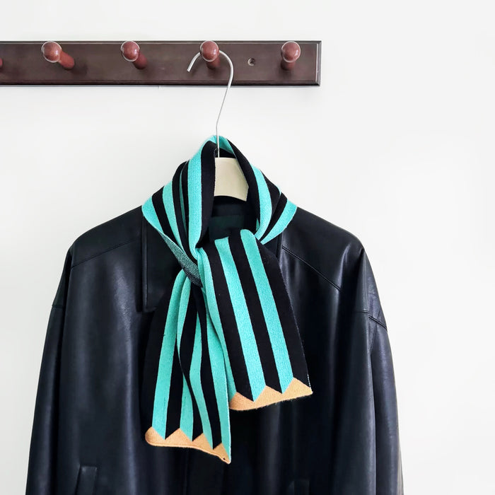 Flat lay of ColorPop Striped Scarf in aqua blue, great for office layering and commuting.