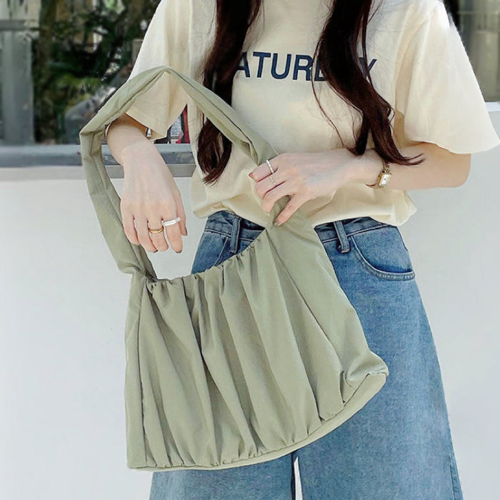 Close-up of  model holding the green pleated bag; highlighting the durable ruched design and spacious interior for daily essentials.