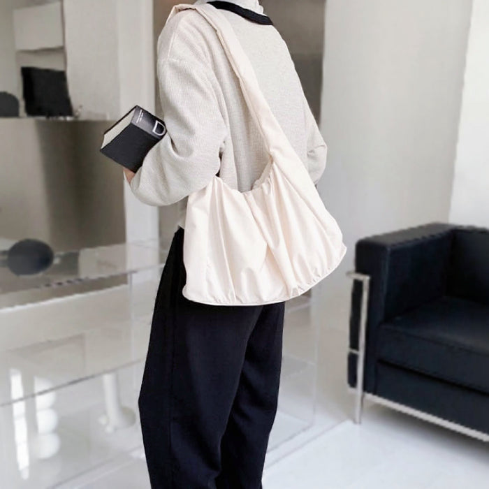 Side view of model styling the cream white pleated bag; versatile neutral accessory for summer outings and minimalist fashion.