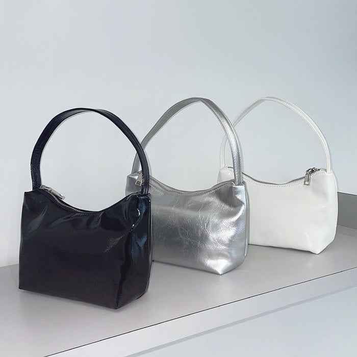 Front view of Three cool patent leather shoulder bags in black, silver, and white, featuring a sleek, compact design.
