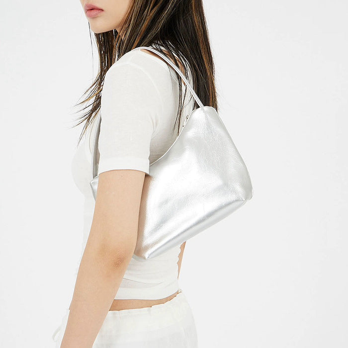 Model carrying a silver  patent leather bag on the shoulder, ideal for city walks and gifting.