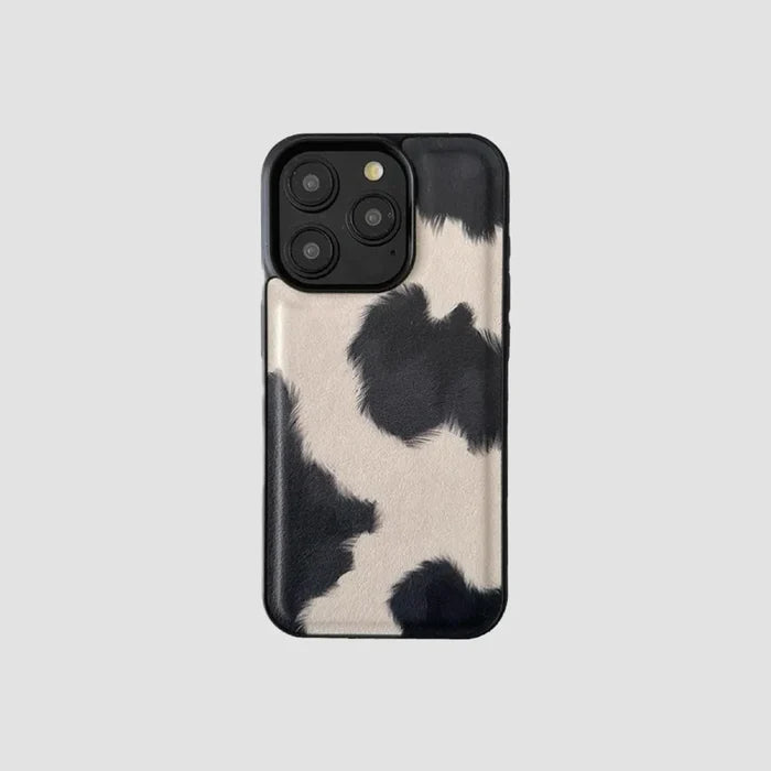 Black and white cow print leather iPhone case. Chic animal pattern with protective black edges and camera trim.