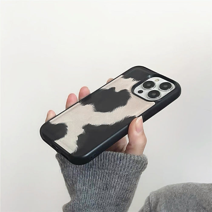 Close-up of Model holding Cow Print Leather Case. Bold high-contrast motif on resilient silicone body.