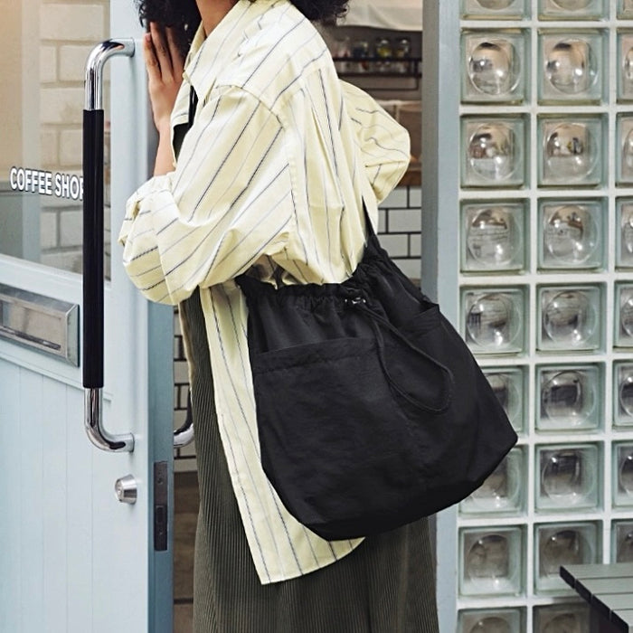Model carrying a black nylon bag as crossbody, easy for commuting and weekends.