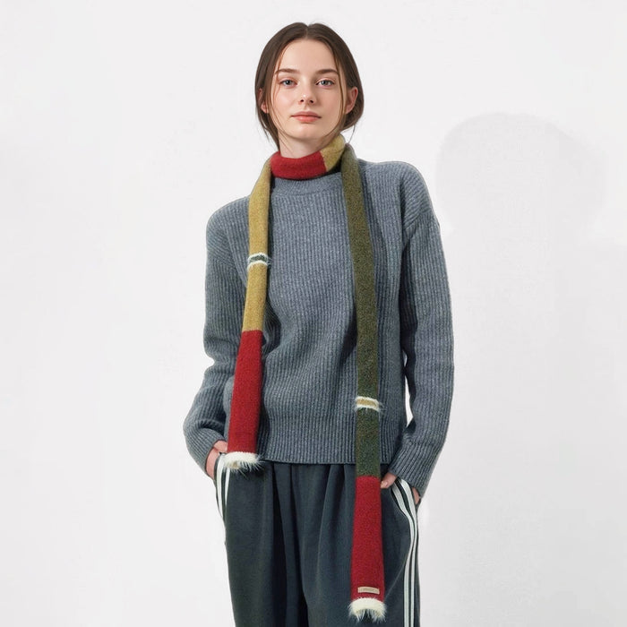Model wearing long, skinny wool-blend scarf with red, olive, and mustard color blocks and white fuzzy ends.