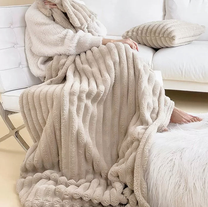 Close up of folded light khaki polar fleece blanket showing wave pattern and soft texture.