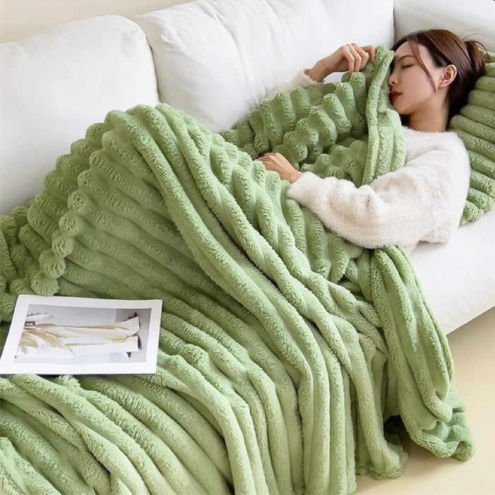Model resting with green wave textured fleece blanket in living room, comfy lifestyle view.