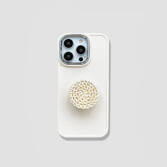 Creamy silicone iPhone case featuring a round woven rattan pop-out stand. Boho chic aesthetic.
