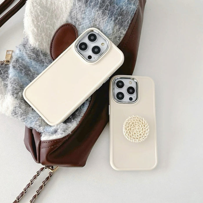 Creamy silicone case with rattan pop socket, shown on a brown bag. Lifestyle flatlay inspiration.
