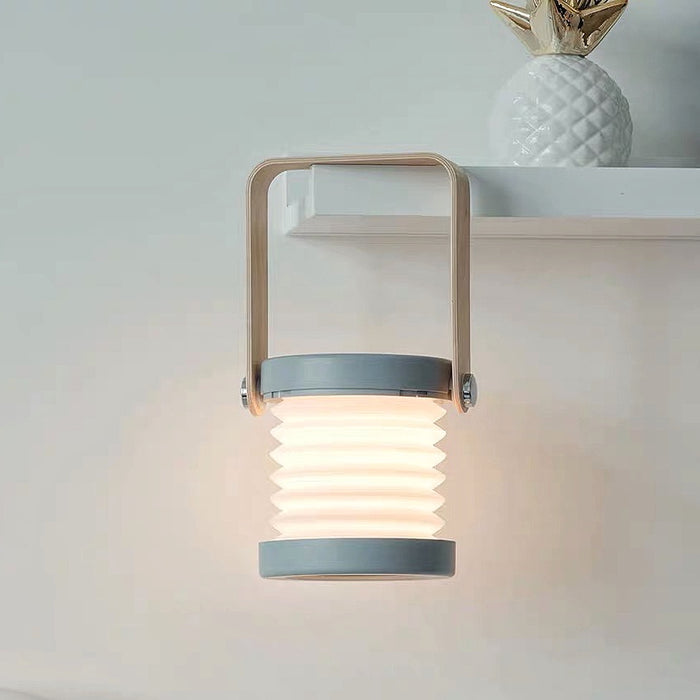 White and wood creative lantern lamp, stretched with glowing LED light, hanging from a shelf.