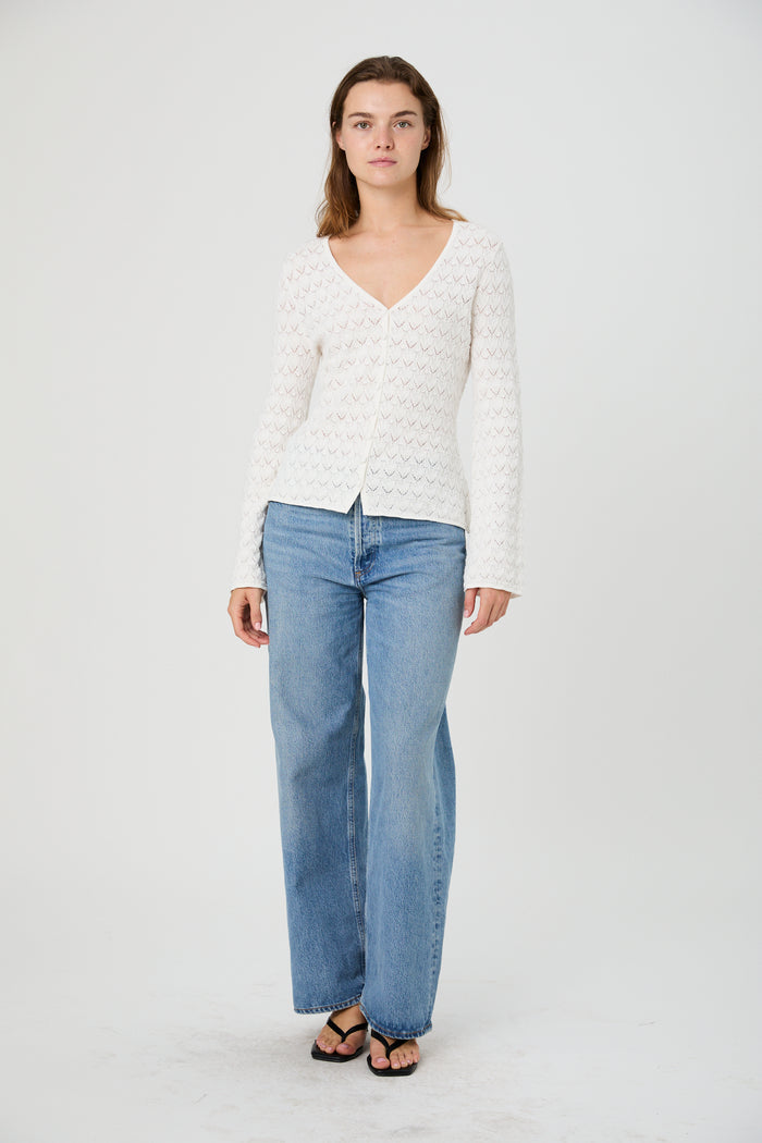 Woman wearing a white sweater and light blue jeans on a white background