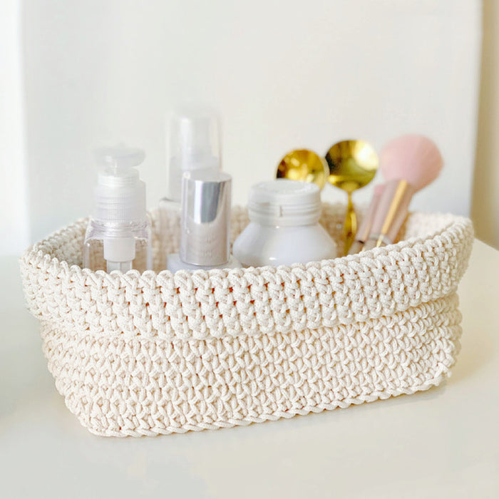Front view of beige crochet storage basket with cosmetics and makeup brushes inside, ideal for tidy shelves and daily use.
