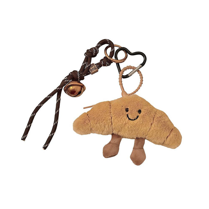 Front view of Fluffy brown polyester croissant bag charm with a smiling face, small feet, and a dark brown rope.