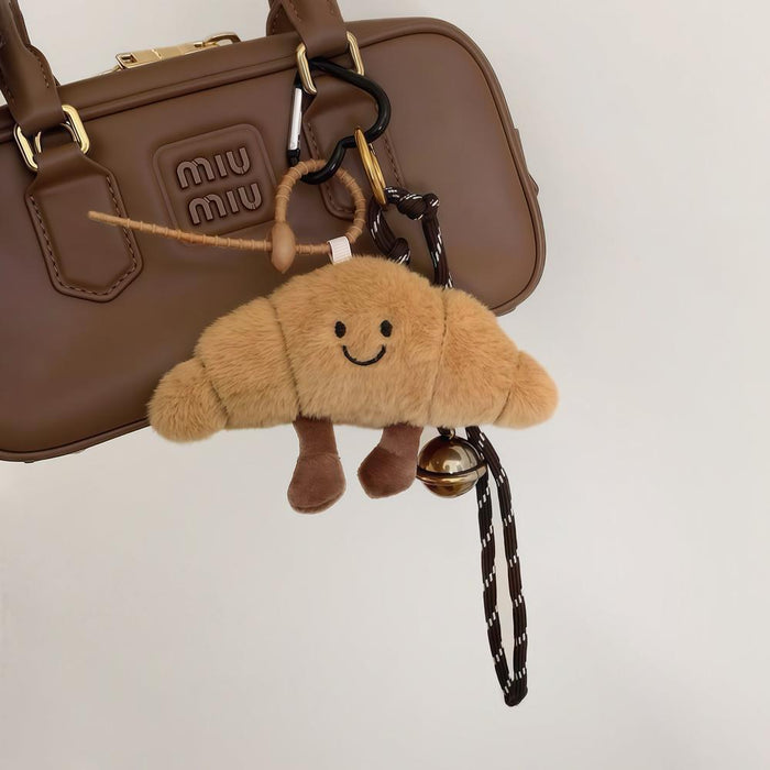 Brown Croissant Bag Charm hanging on a bag, great for winter looks and travel days.