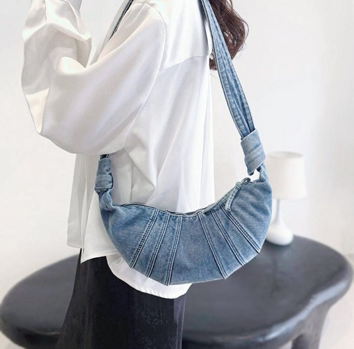 Model carrying a washed blue Croissant Denim Shoulder Bag on the shoulder, easy for commuting and weekends.