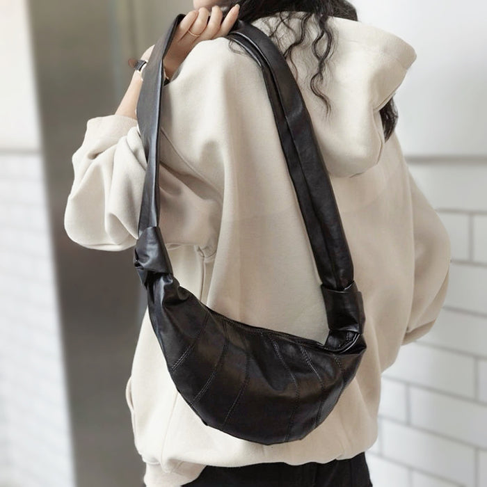 Back view of black pleated leather bag highlighting comfortable shoulder strap and soft tactile structure.