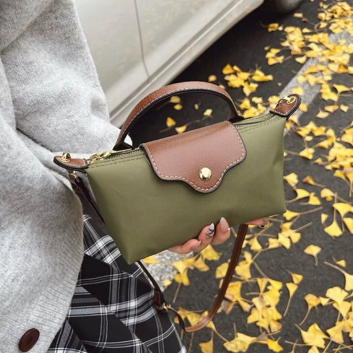 Olive green mini nylon dumpling bag featuring brown leather flap closure and handle.