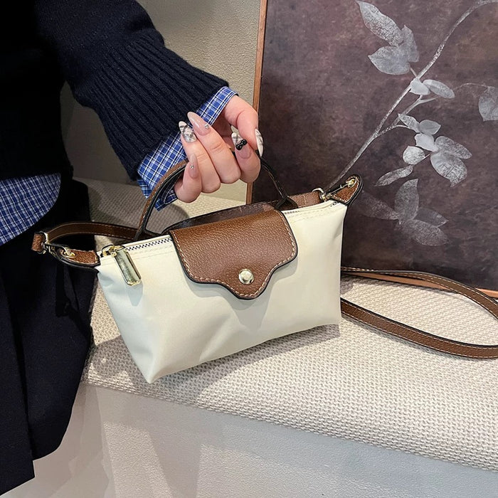 Off-white nylon mini dumpling bag with a brown leather shoulder strap, carried along a street.