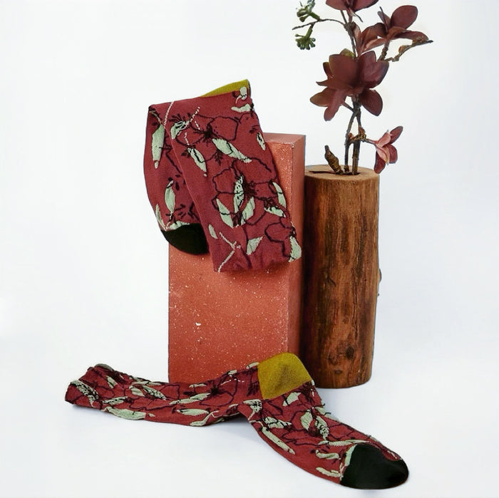 Front view of  red Dancing Flower Socks with green leaf pattern and olive green cuffs.