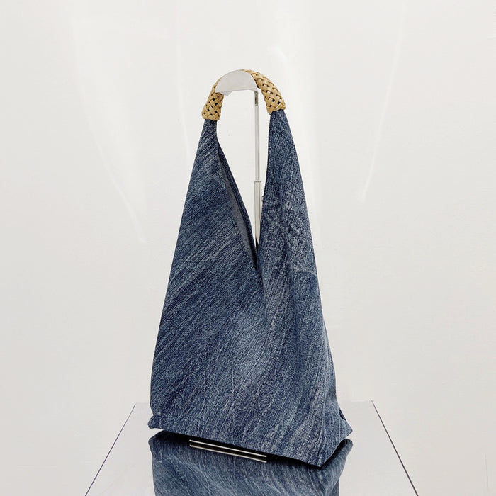 Front view of Denim shoulder bag with a unique triangular shape and braided straw-look handles.