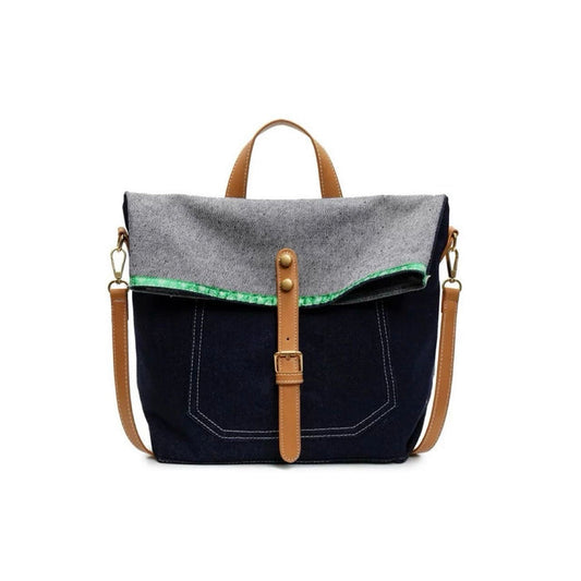 Front view of Denim trimmed messenger bag with gray flap, brown straps, magnetic closure, and green accent.