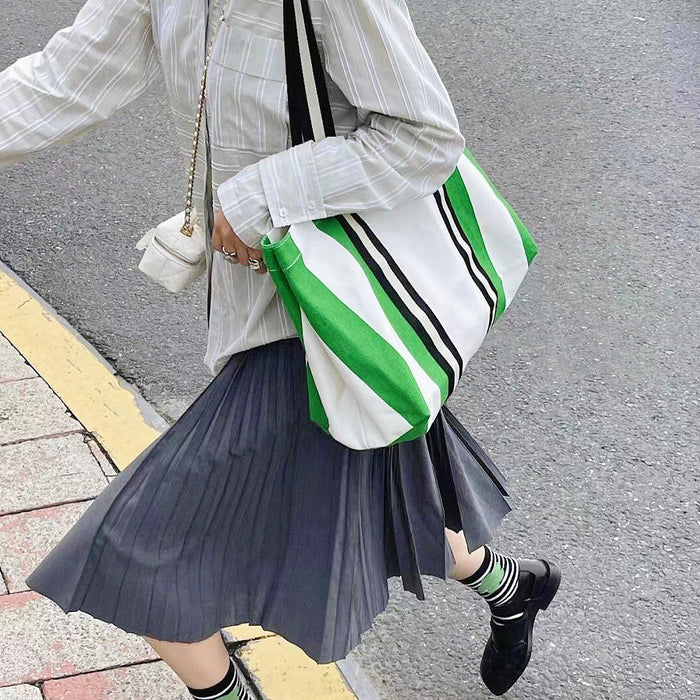 Model carrying the green and white striped canvas tote bag on the street.