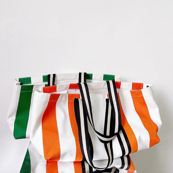 Two designer canvas tote bag are displaying on the table, and the orange tote is in front.