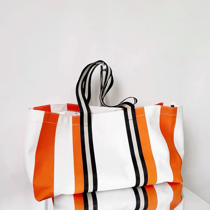 Front view of the designer canvas tote bag with bold orange and black stripes.