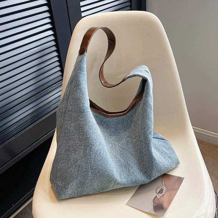 Side view of light blue diamond quilted denim bag, showing spacious structure and leather strap detail