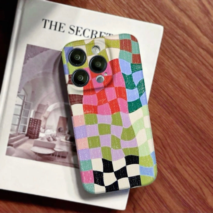A retro-inspired colorful plaid phone case lying on  art magazine, highlighting the distressed texture and artistic vibe.
