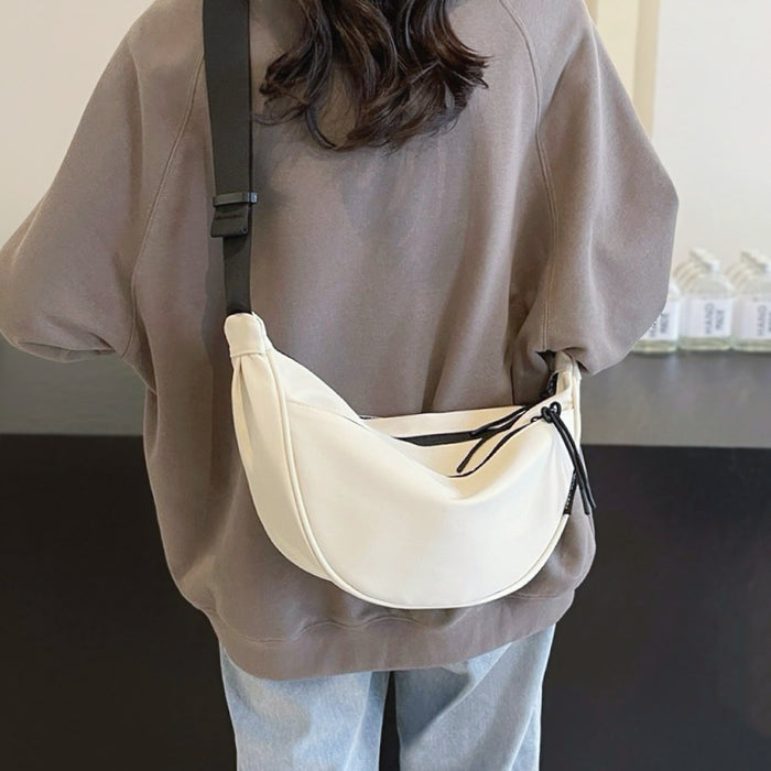 Model styling a white crescent bag over a tan sweater; soft neutral tone suited for spring Office Chic fashion.