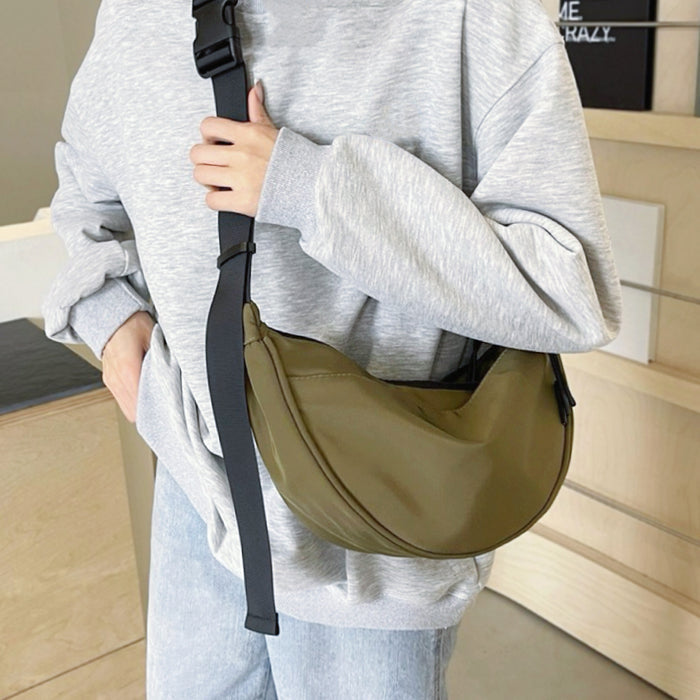 Model with an olive green crescent bag; versatile earth-tone accessory for urban utility and outdoor-inspired looks.