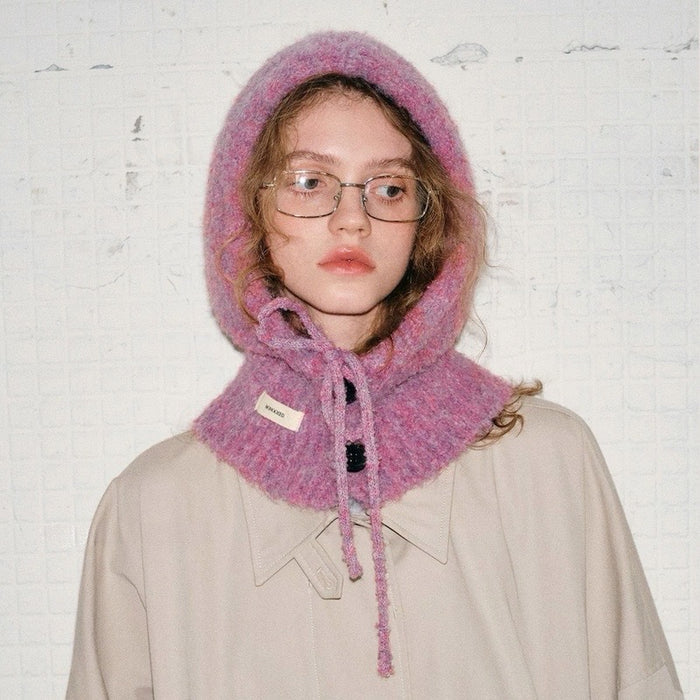 A model wearing a mauve pink buttoned balaclava hat with an adjustable drawstring tie.