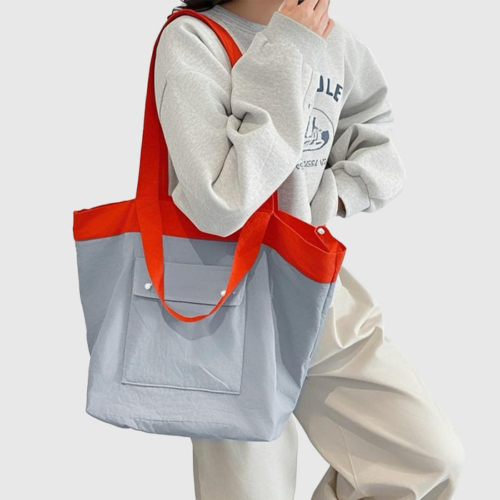 Model carrying a blue duotone foldable nylon tote as shoulder bag, easy for commuting and weekends.