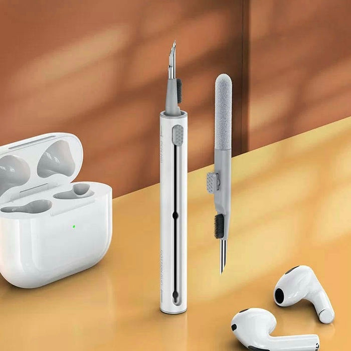 Front view of White dual-head earphone cleaning pen with brush, metal tip, and sponge, next to white earbuds and case.