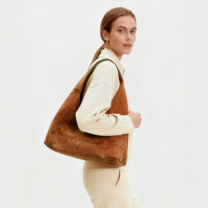 Model carrying the warm tan ease suede hobo bag as a relaxed carryall.