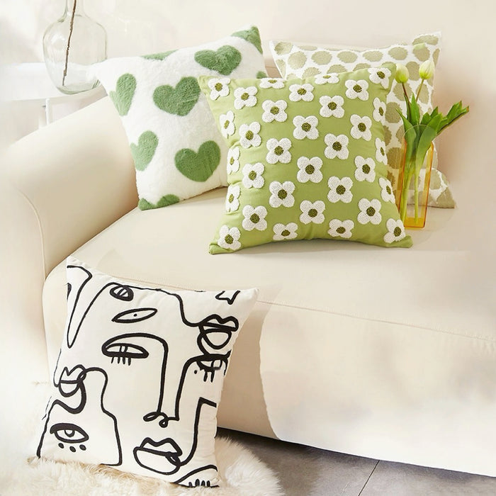 Four pieces of Elegant Vibe cotton pillow covers: green hearts, white flowers on green, and abstract face on white.