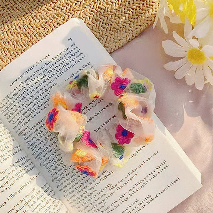 Top view of a floral embroidered scrunchie on a book, showcasing the lifestyle.