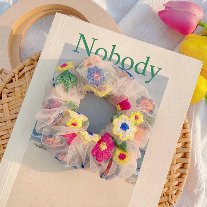 Soft scrunchie on a magazine, featuring intricate floral embroidery details.
