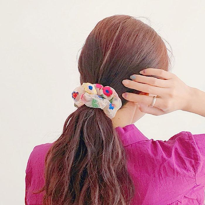 Model styling her ponytail with the voluminous embroidered floral scrunchie.