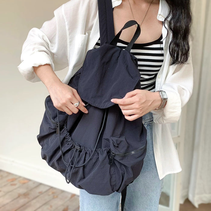 Model styling a black nylon backpack; ultralight material ideal for  city commuting.