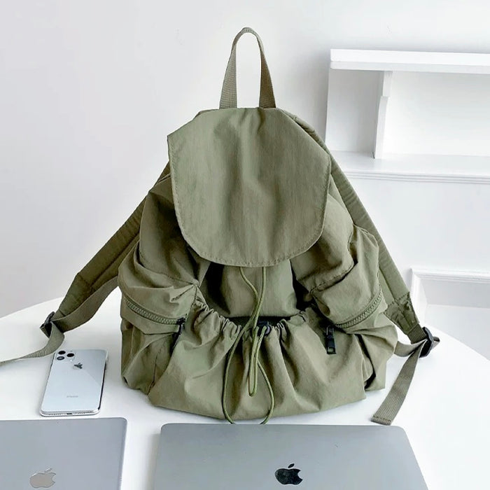 Front view of Olive green ultralight backpack with side zip pockets; durable nylon suited for outdoor-inspired street style.
